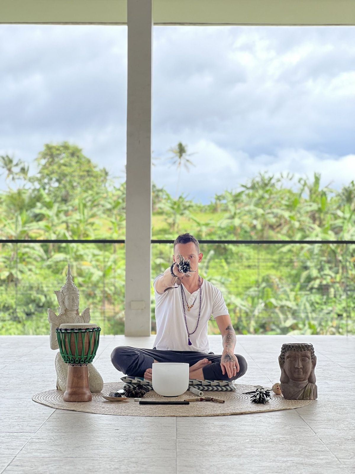 Dylan Ewing seated in meditation with a singing bowl and drum