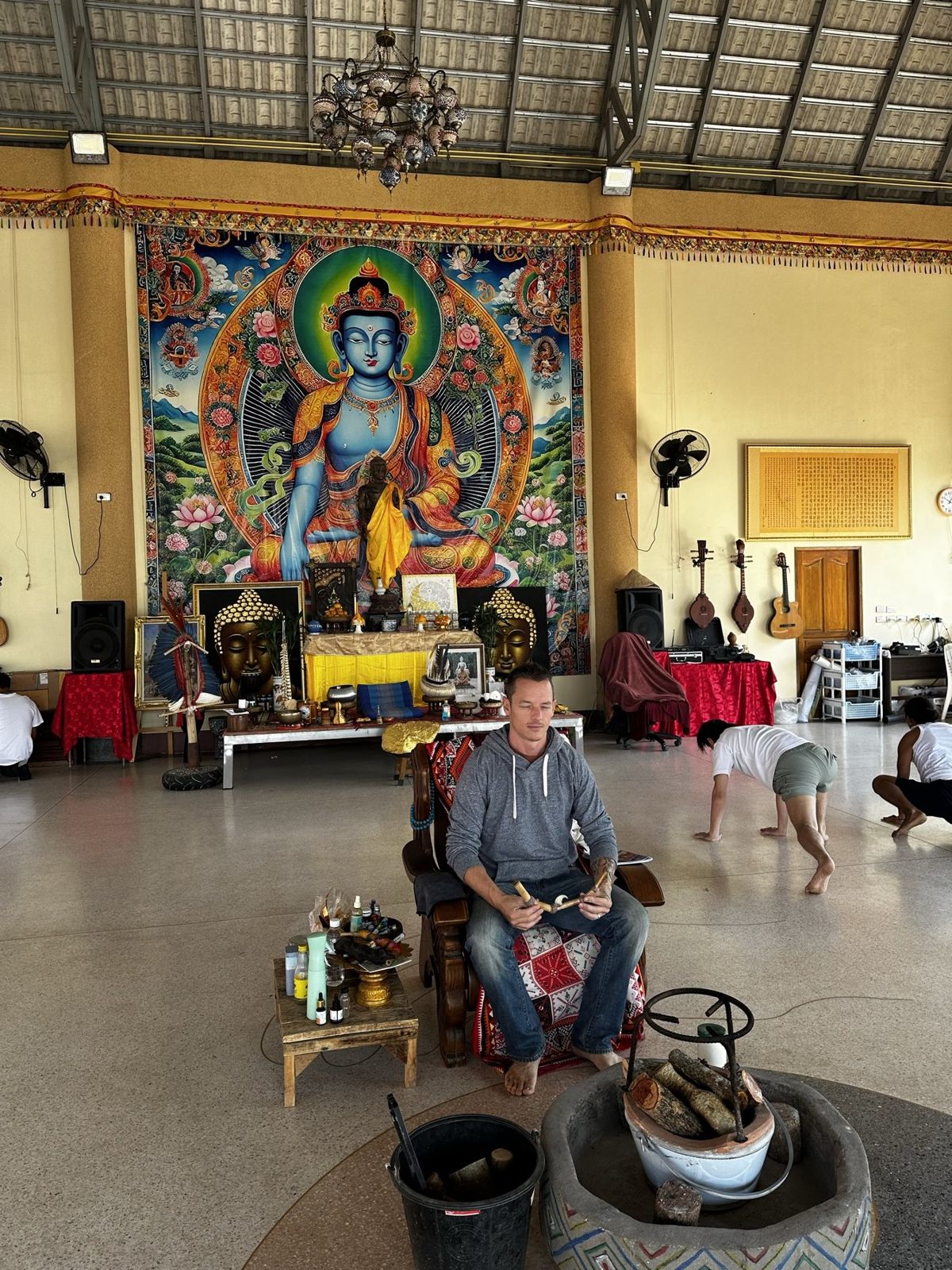Dylan Ewing seated with a drum in a temple hall
